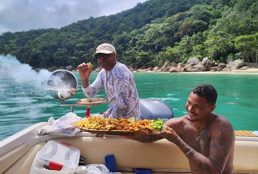 Pessoas fazendo churrasco a bordo de lancha, em passeio em Ubatuba.